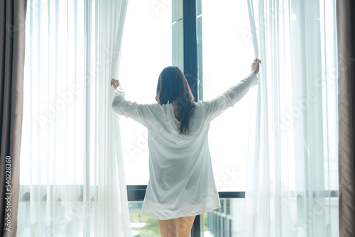 Asian woman standing by the window And stretching in the morning.