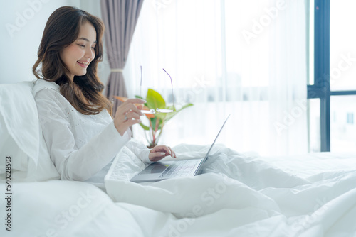 Girl lying in bed playing laptop in bedroom