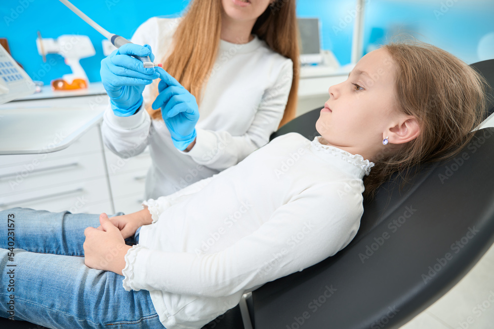 Pedodontist telling about teeth-polishing procedure to little patient