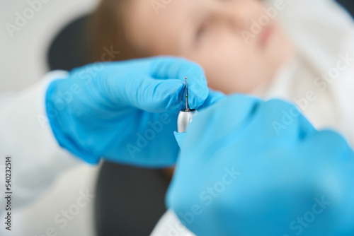 Experienced stomatologist preparing equipment for treatment of patient teeth