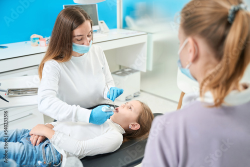 Pediatric dentist administering anesthesia to preteen girl
