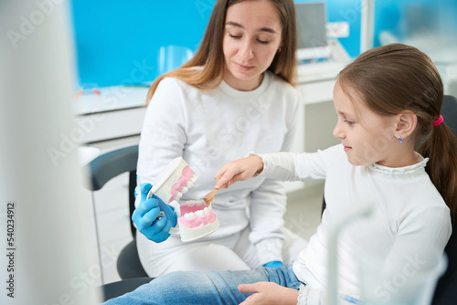 Pre-teen girl learning to clean teeth in dentist office