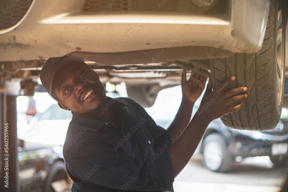 Naklejka premium African maintenance male checking car,service via insurance system at Auomobile repair and check up center