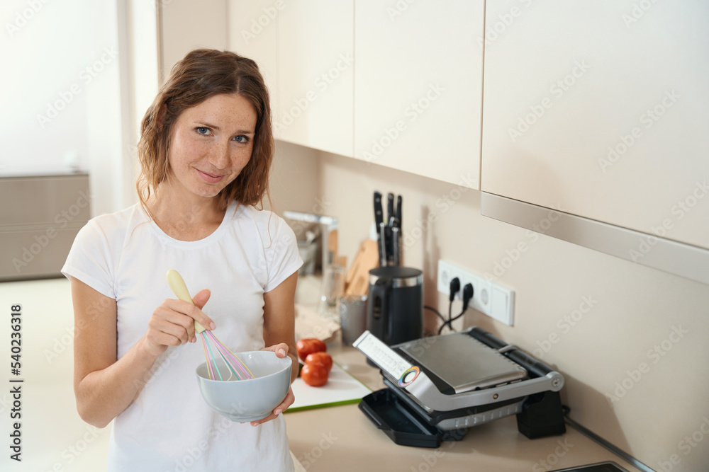 Woman is mixing ingredients for cooking in a deep bowl Woman is mixing ingredients for cooking in a deep bowl