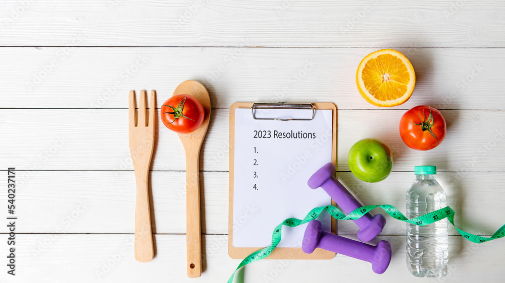 2023 Resolutions.  New year for New Changes Healthy.  Fresh vegetable fruits and healthy food for sport equipment for women diet slimming weight loss on white wood.  Healthy and Holiday Concept