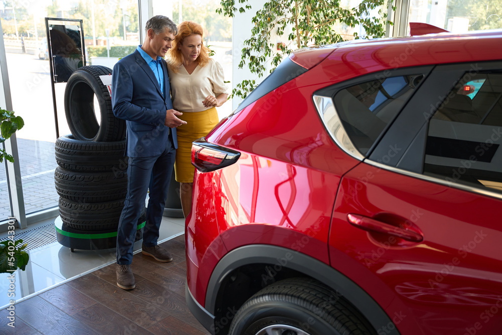 Husband speaking with wife about buy the new red car Husband speaking with wife about buy the new red car