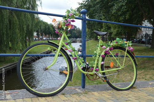 old green bicycle fixed on a bridge and decorated with flowers