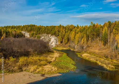 Autumn landscape with river  rock  trees  grass and blue sky