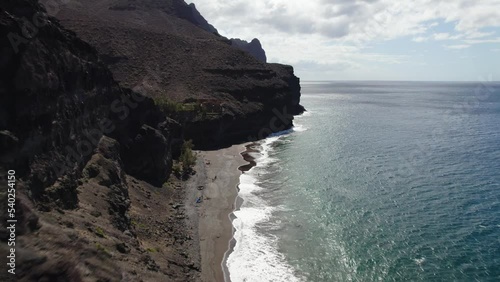Dark sand beach Playa de Guigui in west part of the Gran Canaria island. The beach is accessible only on foot or by boat. Overhead view of huge rocks and cliffs.
 photo