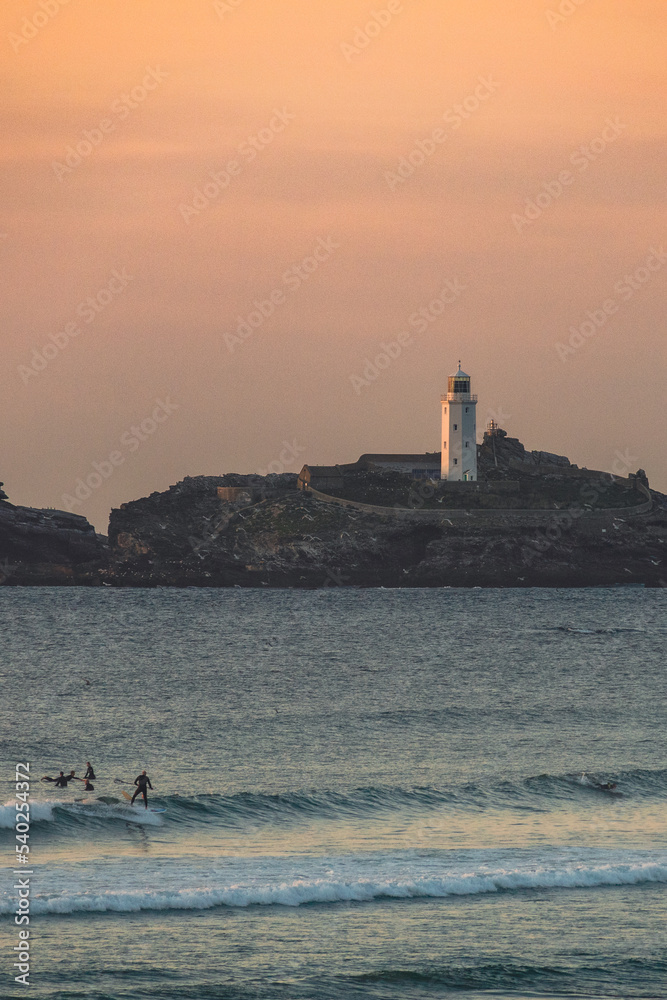 lighthouse at sunset with surfer