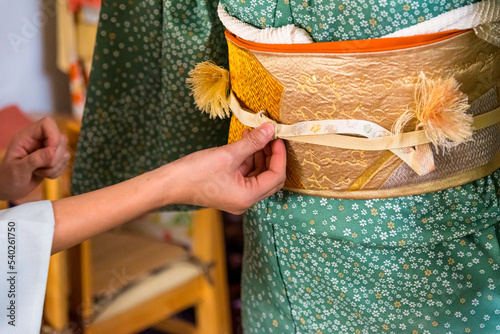 Japanese, Okinawan woman's hands adjusting obijime belt around the obi during traditional kimono dressing