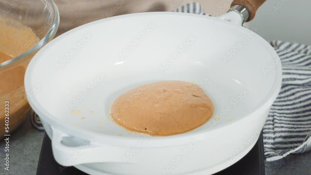 Step by step. Frying pumpkin pancakes batter on a white frying pan. Step by step. Frying pumpkin pancakes batter on a white frying pan.