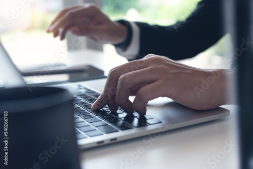 Closeup of businessman working on laptop computer on table at office. Business man hands typing on laptop, online working, surfing the internet at workplace