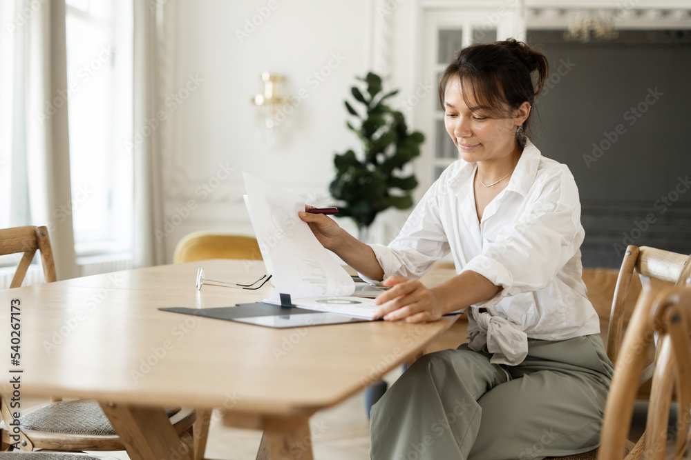 A female freelance designer working at home makes a report on paper. Workplace in the office. A female freelance designer working at home makes a report on paper. Workplace in the office.