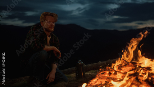 Dreamy hipster enjoy night fire burn on camp site. Closeup traveler in mountains