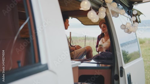 Romantic date out of town. Portrait of beautiful young couple in love talking and smiling. Big white automobile. Camping car. Weekend out of town. Outdoors. Tourism, summertime