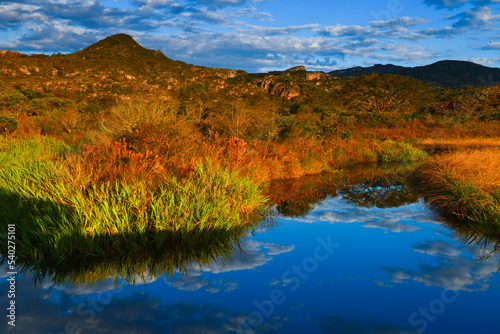 Sunset on a small river surrounded by the rugged landscape and cerrado vegetation of the Serra do Espinhaço range on the way to the historic village of Biribiri, Diamantina, Minas Gerais state, Brazil