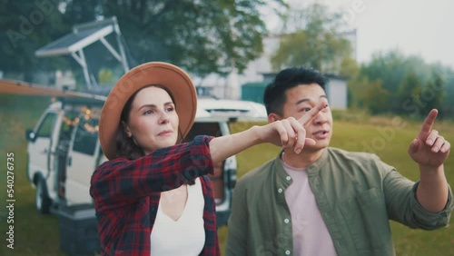 Horizontal view of couple in love spending time together. Pretty woman showing boyfriend around native village. Girlfriend and man talking and laughing. Indoors. Blurred view of camping car