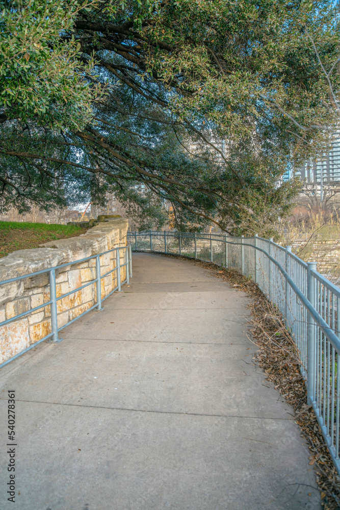 Austin, Texas- Concrete walkway with metal railings along the trees on the side