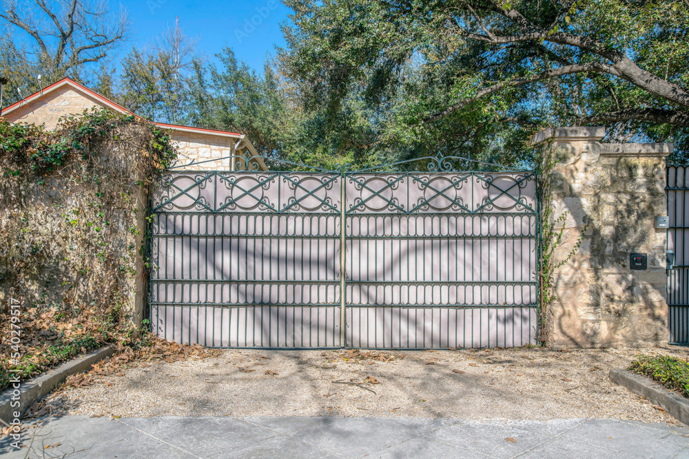 San Antonio, Texas- Wrought iron gate with sheet metal connected to the stone pillar walls San Antonio, Texas- Wrought iron gate with sheet metal connected to the stone pillar walls