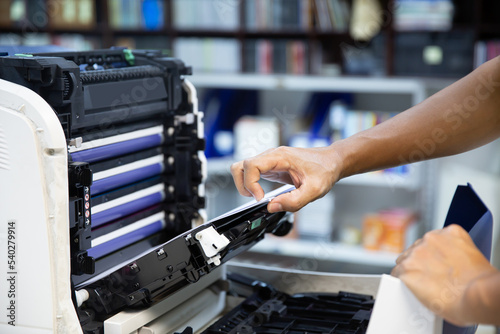 Technician hand open cover photocopier or photocopy to fix copier paper jam and replace ink cartridges for scanning fax or copy document in office workplace.
