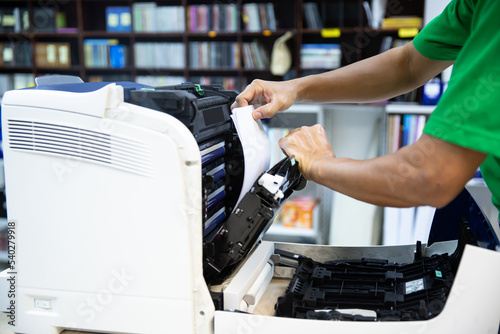 Technician hand open cover photocopier or photocopy to fix copier paper jam and replace ink cartridges for scanning fax or copy document in office workplace.