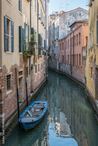 Small boats parked in a typical canal in the heart of Venice, Italy © parkerspics
