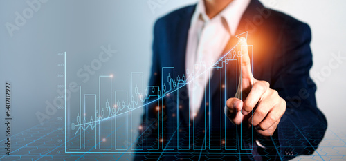 Businessman point to growthing graph and modern computer virtual. Analyzing finance sales data and economic growth graph chart and block chain technology.