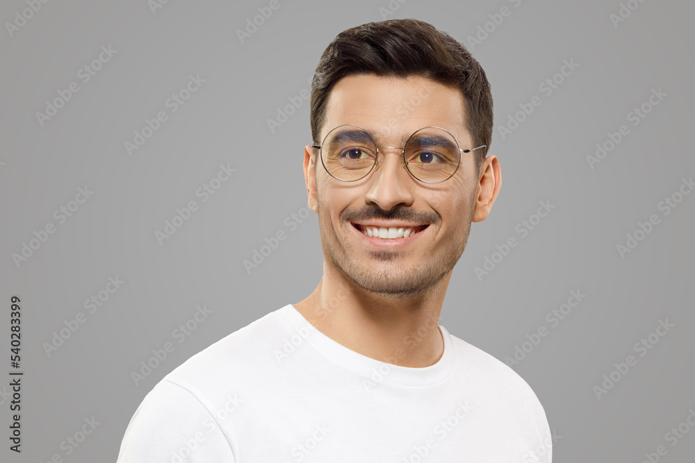 Young handsome man in white t-shirt and glasses looking aside with confident smile, making plans Young handsome man in white t-shirt and glasses looking aside with confident smile, making plans