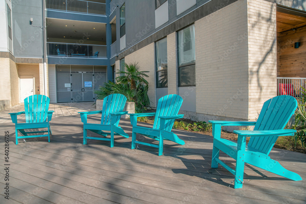 Sky blue wooden lounge arm chairs on a wooden deck outside an apartment building- San Antonio, TX