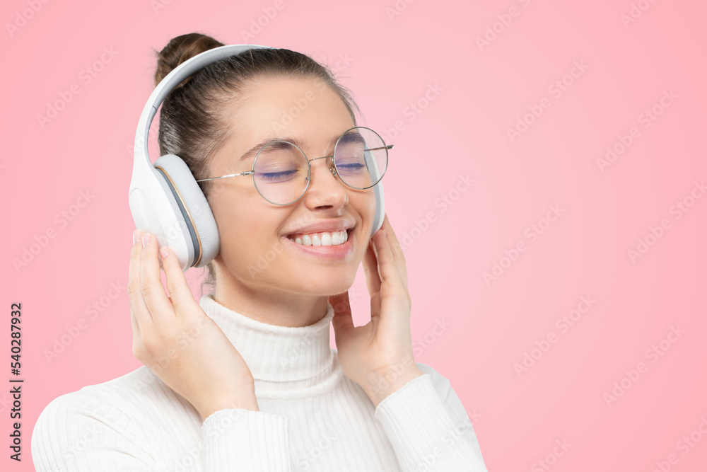 Closeup of girl relaxing to sounds of music in her wireless headphones, smiling with eyes closed Closeup of girl relaxing to sounds of music in her wireless headphones, smiling with eyes closed