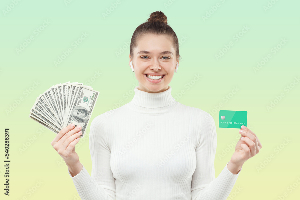Young female smiling holding fan of hundred dollar banknotes and credit card, satisfied with cash Young female smiling holding fan of hundred dollar banknotes and credit card, satisfied with cash