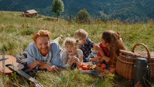 Parents enjoy picnic children lying grass mountain slope. Family resting outdoor