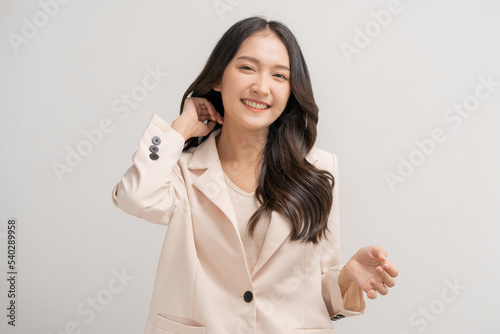 Fototapeta Smiling positive, attractive asian young woman, girl in beige suit formal dress, portrait elegant of pretty with long black hair, feeling happy looking at camera standing isolated on white background