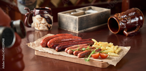 beer plate snacks sausages french fries on a wooden board on a brown table