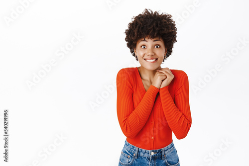Image of african american girl looks excited  tempted to see smth  feeling enthusiastic  standing over white background