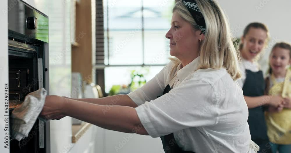 Happy middle aged blonde granny in apron teaching daughter and granddaughter baking cooking homemade domestic cookies biscuits telling private recipe. Happy middle aged blonde granny in apron teaching daughter and granddaughter baking cooking homemade domestic cookies biscuits telling private recipe.
