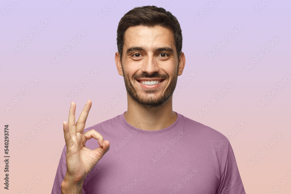 Young smiling man having happy look, gesturing, showing OK sign or gesture with his fingers Young smiling man having happy look, gesturing, showing OK sign or gesture with his fingers
