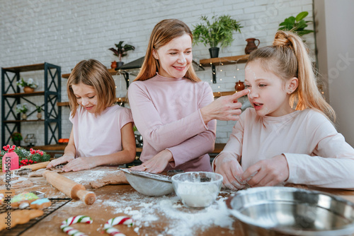 Mother with daughters cooking Christmas gingerbread cookies
