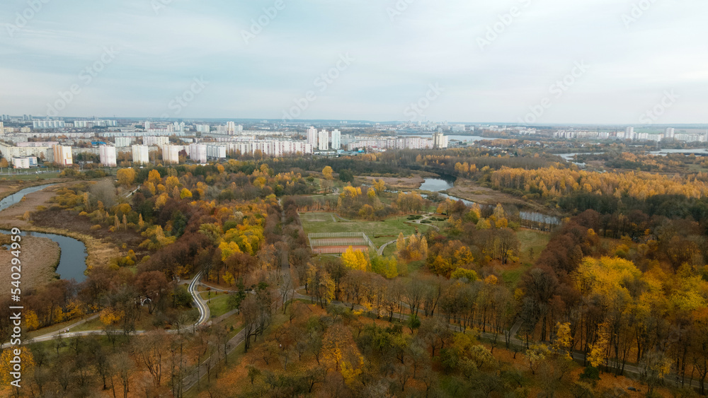 Autumn city park. Trees with colorful leaves. Sports grounds. Autumn landscape. Aerial photography. Flight with slow camera down.