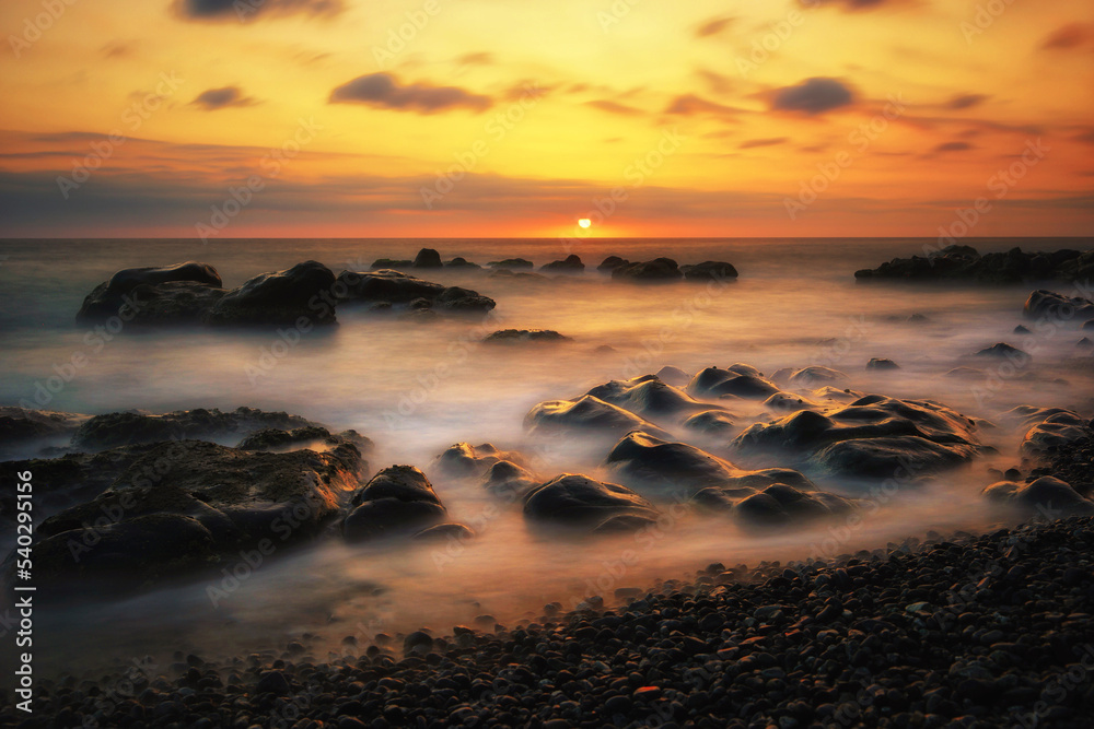 sunset over the sea, waves crashing on stones, long exposure sunset over the sea, waves crashing on stones, long exposure