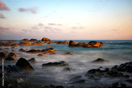 sunset over the sea, waves crashing on stones, long exposure