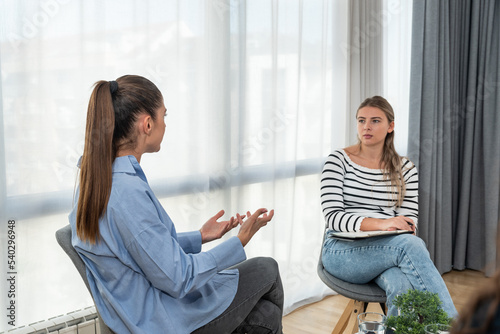 Young woman victim of domestic violence or robbery or mobbing at work talks to an expert psychotherapist for therapy in a comfortable apartment. Psychologist discuss mental problems trauma after shock photo