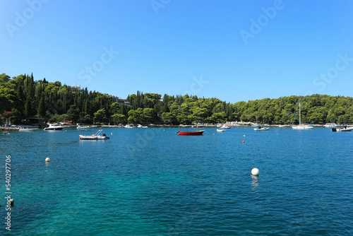 View of boat in port in small coast town with clear water and green Mediterranean forest