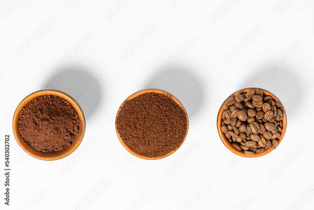 Three cups of coffee beans, ground coffee and cocoa for comparison.