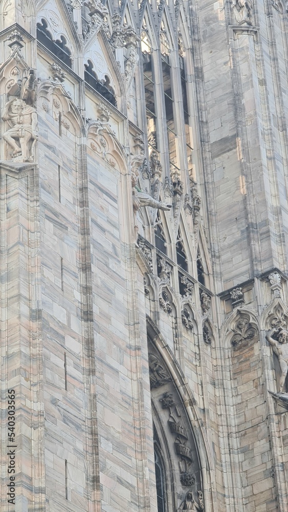 Milan Italy- October 17, 2022: Milan cathedral Duomo di Milano with gothic spires and white marble statues. Top tourist attraction on piazza in Milan, wide angle view of old gothic architecture.