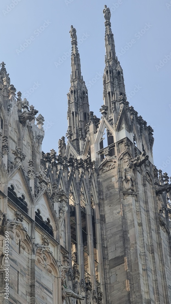 Milan Italy- October 17, 2022: Milan cathedral Duomo di Milano with gothic spires and white marble statues. Top tourist attraction on piazza in Milan, wide angle view of old gothic architecture.