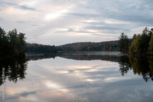 Clouds reflecting on a calm  tree lined lake. Maple Leaf Lake  Algonquin Provincial Park  Ontario  Canada.