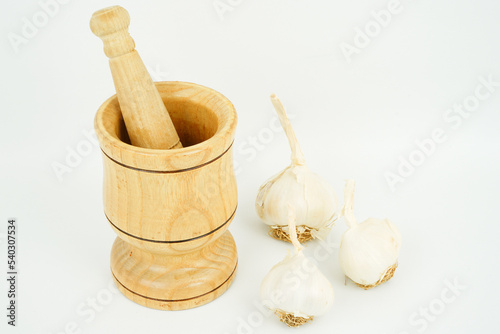 garlic and garlic masher in front of white background