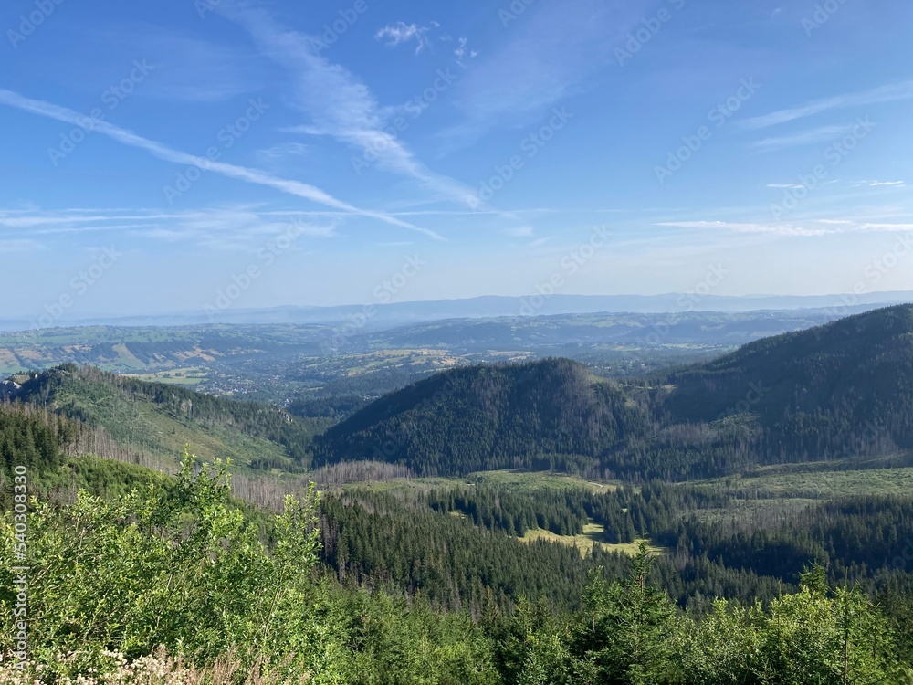 Naklejka premium Summer day blue sky mountains landscape. Nature landscape with sun and blue sky. Summer travel in Europe mountains. Nature, lake, forest, trees hiking path. Clouds on blue sky. Forest landscape hiking